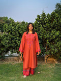 Woman in a red traditional outfit standing outdoors with greenery in the background